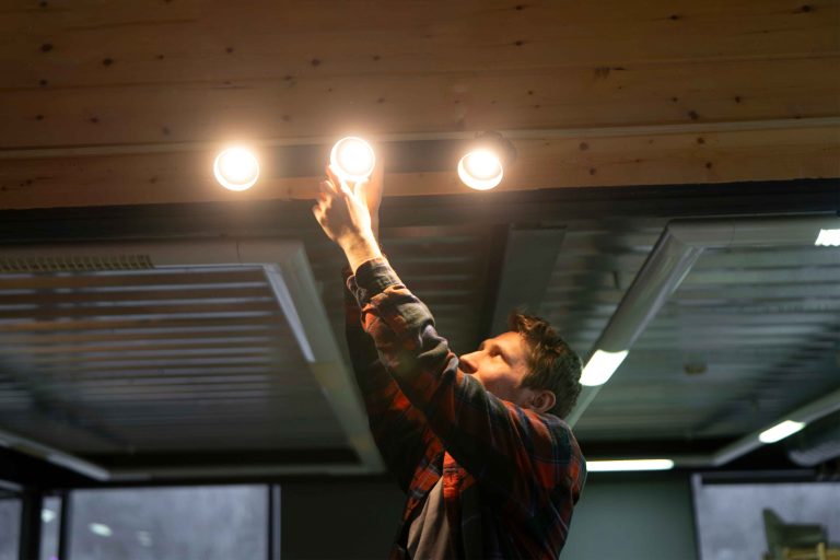 a-man-reaches-up-to-replace-a-light-bulb-in-the-ce-2026-01-07-01-25-45-utc_11zon
